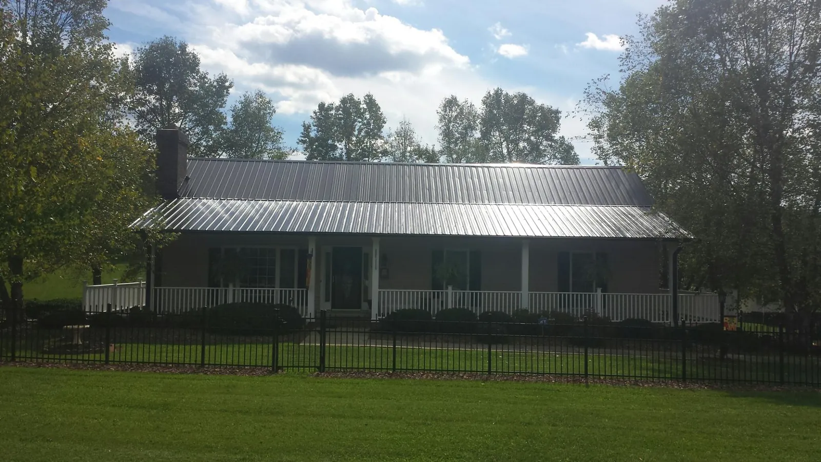 Gray metal roof on a brick ranch with a full width front porch — Gutter Guard Installation work by our crew in Sheakleyville