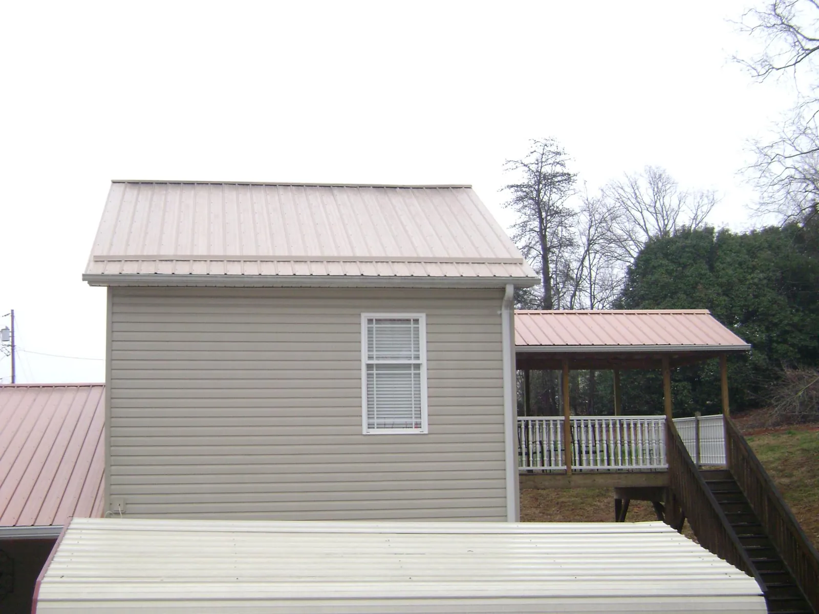 Tan metal roofs on a two story addition and attached porch, from a Roof Replacement job in Sheakleyville