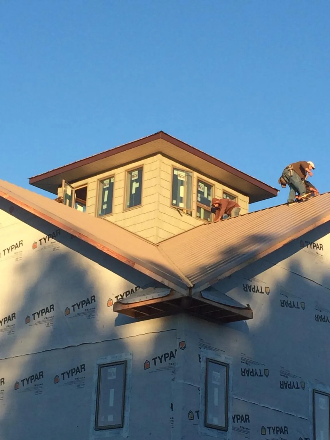 Roofers working around a rooftop cupola on a new metal roof at sunset — Roof Waterproofing in Sheakleyville by Roofing Brothers